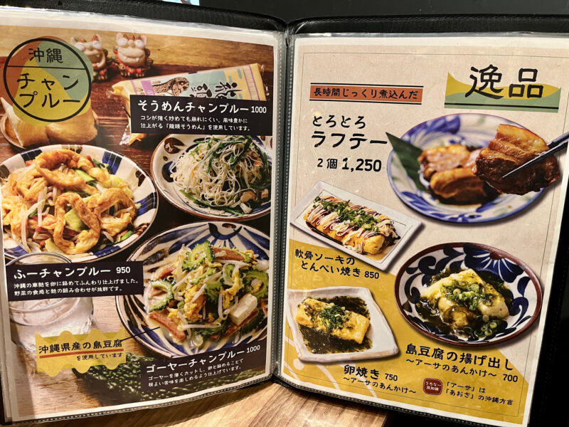 沖縄料理「ハイサイ」のメニュー写真。チャンプルーやラフテーなどの料理写真と価格が載っている。