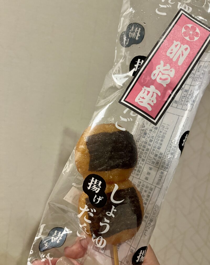 揚げだんごを手に持った写真。包み紙には「しようゆ だんご」「揚げだんご」と書かれている。