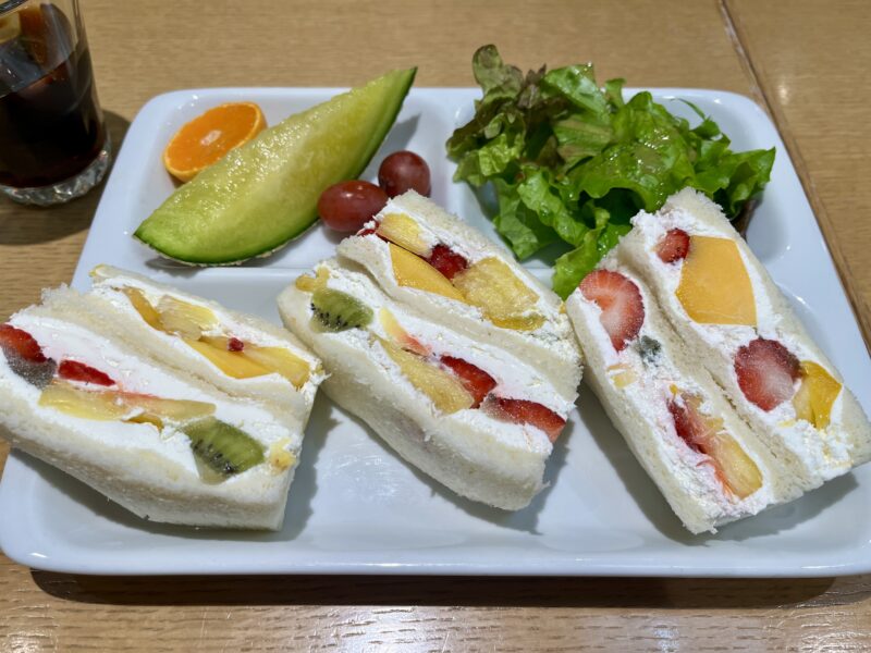 フルーツたっぷりのフルーツサンド（生クリーム入り）と、サラダ・メロン・ぶどう・みかんが添えられたモーニングプレート。